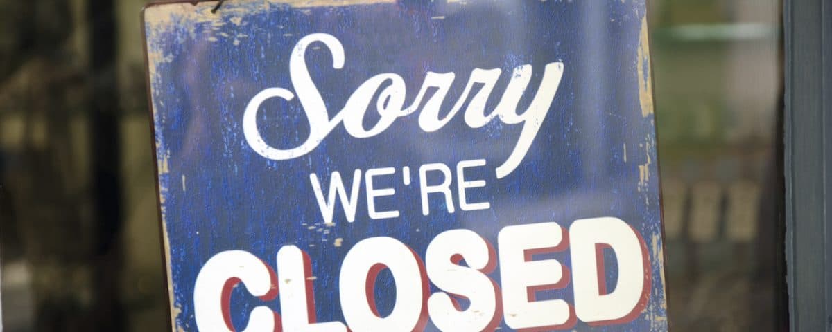 Old blue closed sign hanging in a shop window